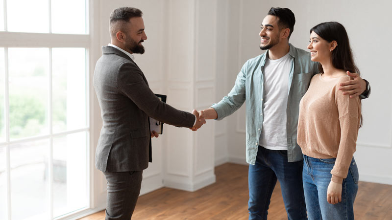 Casal a apertar a mão a vendedor imobiliário